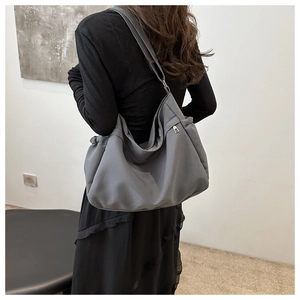 Side view of large dark grey nylon tote bag with adjustable strap on a model