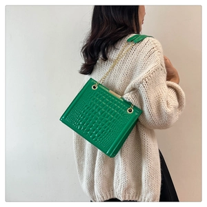 Detail of bright green croc-embossed texture and gold chain on a stylish tote bag