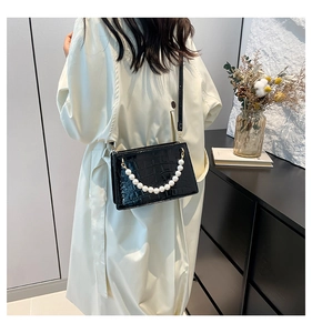 Detail shot of black crocodile embossed crossbody bag with faux pearl handle decoration