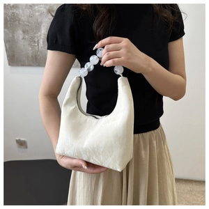 Detail of white crescent bag with marble texture and elegant large beaded handle