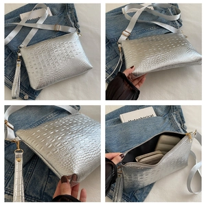 Macro detail of silver crocodile pattern envelope bag with gold hardware and strap