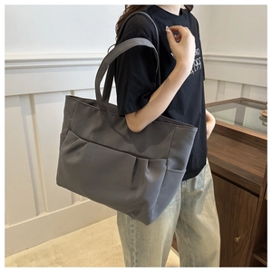 Détail du sac cabas gris foncé avec poches avant plissées et tissu en nylon résistant