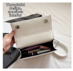 Vue intérieure du sac bandoulière blanc montrant l'espace de rangement pour cosmétiques