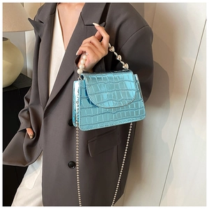 Detail of light blue croc-embossed mini bag with pearl heart handle and silver chain strap
