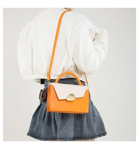 Vue arrière du mannequin portant un sac bandoulière bicolore orange et crème à boucle