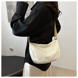 Detailed view of cream nylon dumpling bag featuring textured geometric weaving and strap