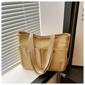 Détail du sac cabas en toile jaune avec poches frontales et rivets métalliques argentés