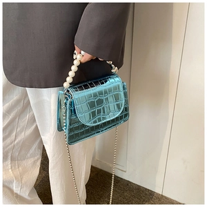 Detail of bright blue croc-effect mini bag with pearl handle and silver chain strap
