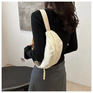 Macro detail of beige crossbody bag featuring textured geometric fabric and woven zipper pull