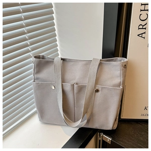 Détail du sac cabas en toile grise avec poche avant fonctionnelle et bouton pression en métal