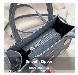 Close-up of smooth silver metal zipper and denim texture on blue fashion handbag