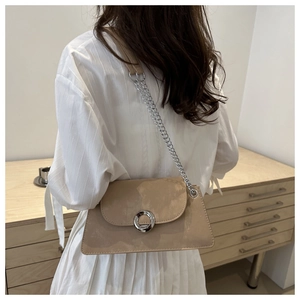 Détail du sac bandoulière en daim abricot avec chaîne argentée et boucle métallique