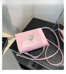 Detail view of pink leather crossbody bag featuring unique irregular metal buckle on flap