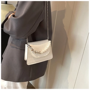 Detail of white crocodile pattern mini bag with pearl chain straps on a model