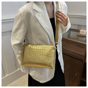Detailed view of a gold crocodile pattern envelope bag styled with a white blazer