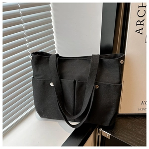 Détail du sac cabas en toile noire avec deux poches avant et sangles en tissu robuste