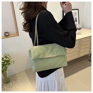 Detail of sage green quilted crossbody bag featuring elegant gold chain strap and metal clasp