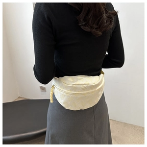 Detail of light yellow textured waist bag with 3D woven pattern and zipper pull