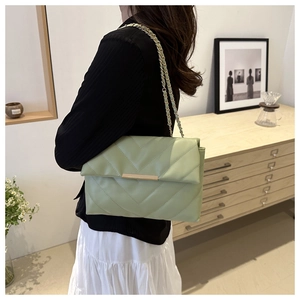 Dettaglio ravvicinato della borsa trapuntata verde chiaro con tracolla a catena dorata su modella
