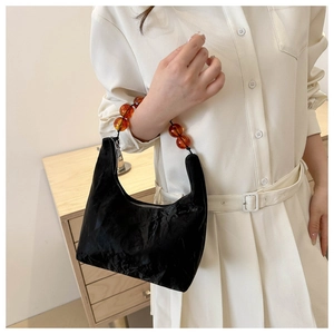 Detail of black crescent bag with vintage texture and amber beaded handle