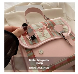 Detailed macro view of the metal magnetic snap closure on a pink plaid mini backpack