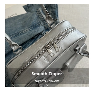 Nahaufnahme der silbernen Tasche mit Doppelreißverschluss und eleganten Nähten am Rand