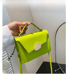 Detail of green patent leather mini square bag with silver clasp and top handle strap
