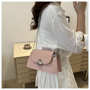 Détail d'un sac porté épaule en daim rose avec boucle argentée et bandoulière en chaîne
