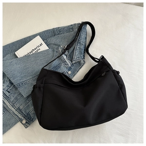 Detail of black crossbody tote bag featuring drawstring side pockets and adjustable strap