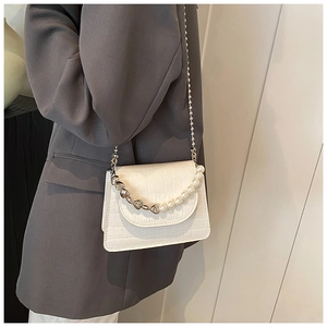 Detail of white crocodile pattern bag with unique pearl and silver chain handle