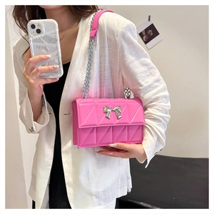 Sac bandoulière matelassé rose avec nœud argenté porté sur un blazer blanc chic