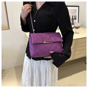 Dettaglio borsa in pelle viola trapuntata a V con chiusura dorata e tracolla a catena