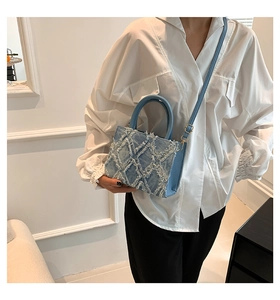 Nahaufnahme der hellblauen Denim-Umhängetasche mit ausgefranster Rautenstruktur und Golddetails