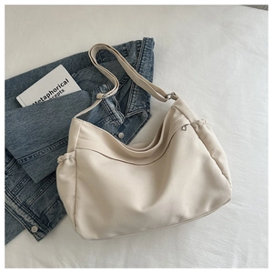 Detail of off-white tote bag featuring side drawstring accents and adjustable strap