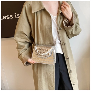 Détail d'un mini sac à rabat argenté à motif crocodile et élégante chaîne de perles