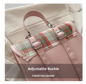 Macro detail of pink backpack with plaid flap and silver metal adjustment buckles