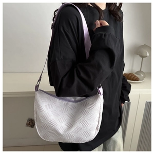 Detail of white woven texture crossbody bag with purple fabric strap on model
