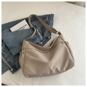Detail of beige canvas crescent tote with adjustable strap and side drawstring pockets