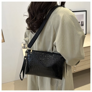 Details der schwarzen Briefumschlagtasche mit Kroko-Prägung und goldenem Reißverschluss