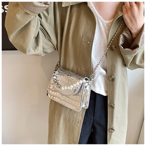 Detail of silver crocodile pattern mini bag with pearl chain and metal strap on model