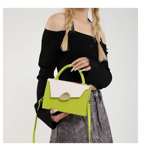 Détail du sac bandoulière bicolore vert avec un fermoir en métal doré en forme de galet
