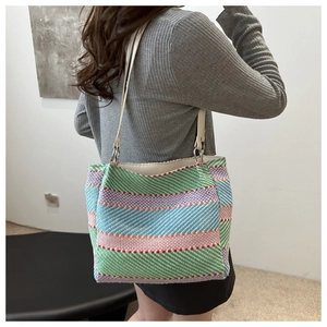 Close-up of rainbow striped woven tote bag with white shoulder straps on model