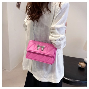 Détail du sac à bandoulière en cuir matelassé rose avec nœud argenté et chaîne