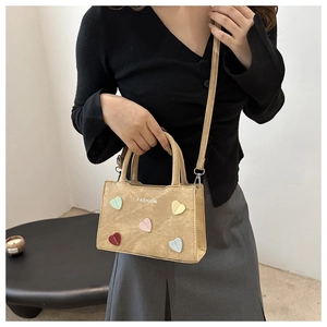 Detail of khaki bucket bag featuring five colorful heart patches and Fashion print