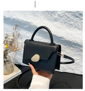 Detail of black crossbody bag with matte leather texture and golden metal buckle
