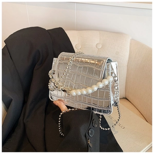 Detail of silver crocodile pattern mini flap bag with pearl handle and metal chain strap