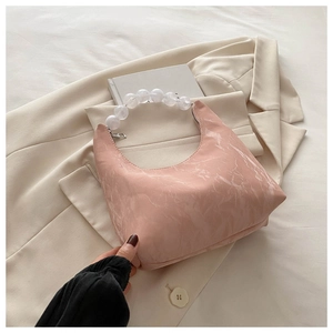 Detail of pink marble pattern handbag with transparent beaded handle on beige blazer