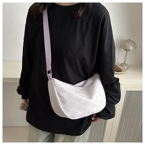 Close-up of white quilted crossbody bag with a purple strap in a modern room setting
