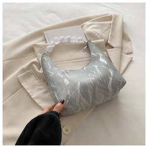 Detail of silver crescent bag with white bead handle and crinkled metallic texture