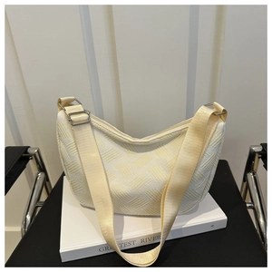 Close-up of cream nylon dumpling bag featuring textured fabric and adjustable strap